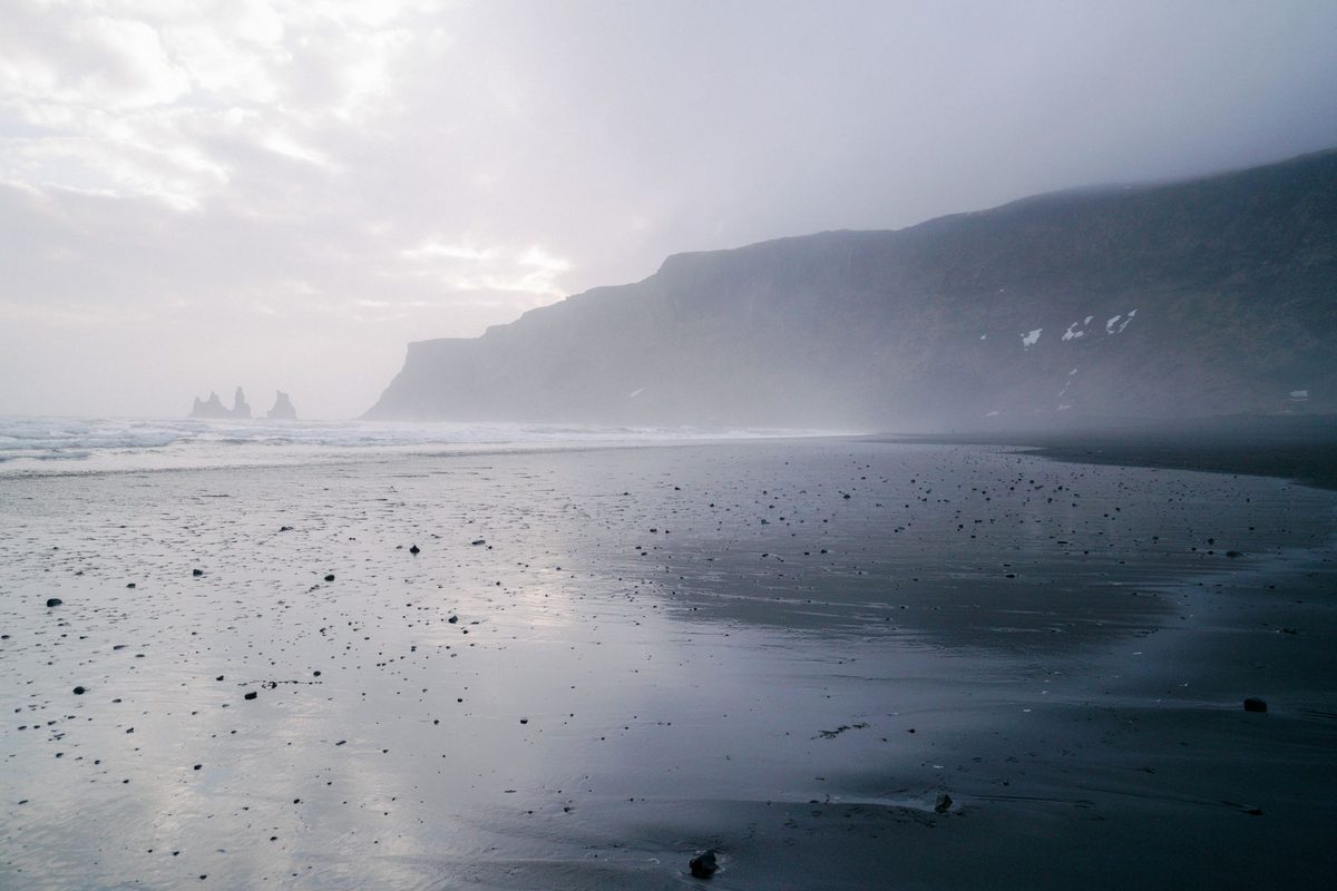 Mlžná černá pláž s osamělou postavou krajiny — Death Stranding 2